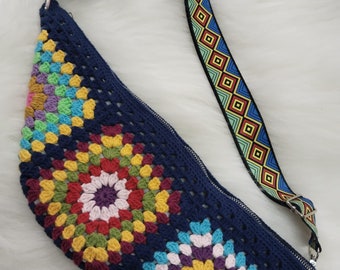 Handmade bum bag knitted with colorful cotton yarn, featuring colorful motifs, a zipper, lining, and adjustable colorful strap.