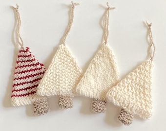 Puede incluir: Cuatro adornos de árbol de Navidad de punto, tres son blancos y uno es de rayas rojas y blancas.