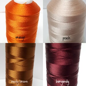 May include: Four spools of embroidery floss in orange, peach, rusty brown, and burgundy.