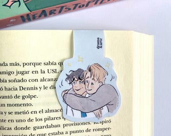 Peut inclure: Un marque-page bleu et blanc avec une illustration de deux hommes qui s'embrassent. Le marque-page porte l'inscription "drama & arte".