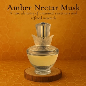 May include: A clear glass bottle of perfume with a gold top and a wooden base. The bottle is filled with a light yellow liquid. The text "Amber Nectar Musk" is written in black at the top of the image. The text "A rare alchemy of untamed sweetness and refined warmth" is written in black below the product name.