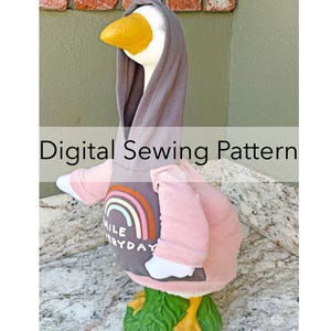 May include: A decorative goose statue wearing a gray hoodie and a pink shirt with a rainbow design and the words "Smile Everyday." The goose has a yellow beak and is standing on a green base. Text on the image reads "Digital Sewing Pattern."