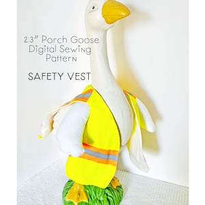 May include: A white goose statue wearing a bright yellow safety vest with reflective stripes. The goose has a yellow beak and is standing on a green base. Text on the image reads "23" Porch Goose Digital Sewing Pattern" and "SAFETY VEST".