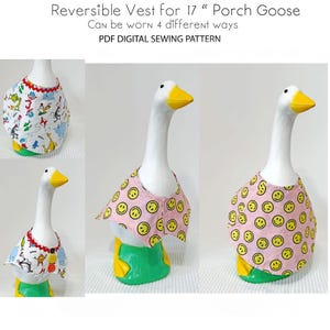 Puede incluir: Un ganso de cerámica blanco con un chaleco reversible. El chaleco tiene un fondo rosa con caras sonrientes amarillas. El texto de la imagen dice "Reversible Vest for 17" Porch Goose" y "Can be worn 4 different ways".