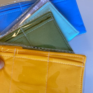 May include: Four fabric face masks in individual clear plastic packaging. The masks are yellow, green, light blue, and white with a floral pattern.