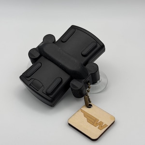 May include: Black car phone mount with a suction cup and a small wooden tag with a winged "W" logo.