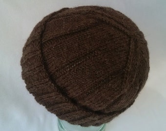 May include: A brown knitted beanie hat with a ribbed texture. The hat is folded down at the brim.