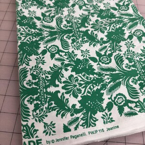 May include: White fabric with a repeating green floral pattern. The fabric has a detailed design of leaves, flowers, and vines. The text "MADE by © Jennifer Paganelli. PWJP 115 Jeanine" is printed on the edge of the fabric.