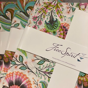 Puede incluir: Un montón de cuadrados de tela con un patrón floral en tonos de rosa, verde y azul. La tela está etiquetada con "Free Spirit" con la dirección del sitio web "freespiritfabrics.com" y el hashtag "#freespiritfabrics".