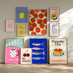 Peut inclure: Plusieurs impressions d'art encadrées avec des illustrations de nourriture et de boissons. Les impressions incluent un citron sur une grille bleue, des tomates, des cerises, des bretzels, du poisson, de l'avocat, du café et des crêpes. Les impressions sont de couleurs variées.
