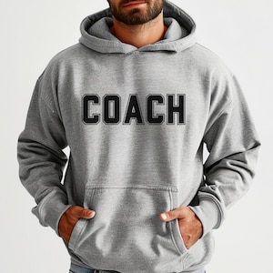 May include: A grey hooded sweatshirt with the word "COACH" printed in black on the front.