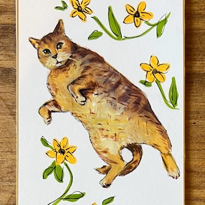 May include: A rectangular art print on white paper featuring a brown tabby cat lying on its side. The cat is surrounded by five hand-painted yellow flowers with green stems and leaves. The illustration uses visible brushstrokes and black ink outlines.