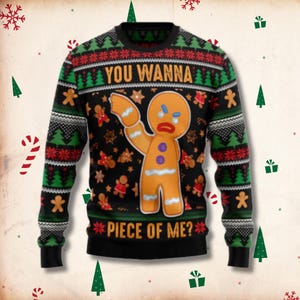 May include: A black long-sleeve crewneck jumper featuring a repeating pattern of green pine trees and red snowflakes. The centre displays a large gingerbread man with an angry expression and the text "YOU WANNA PIECE OF ME?" in yellow.