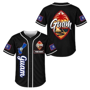 May include: A black baseball jersey featuring white piping, the word Guam in script, a map of Guam, and the Guam flag on the sleeves. The back displays a large emblem with a palm tree, a boat, and the text Guam. A box labeled YOUR NAME is included.