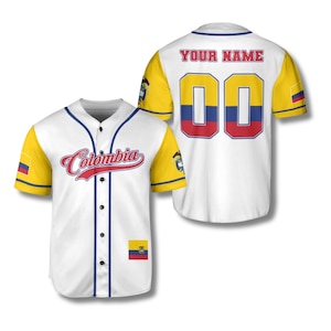 Peut inclure: Maillot de baseball blanc avec des manches jaunes et une bordure bleue. Le devant porte le mot "Colombia" en script rouge. Le dos porte le texte "YOUR NAME" au-dessus du numéro "00" aux couleurs du drapeau colombien. Un petit drapeau colombien est sur la manche.