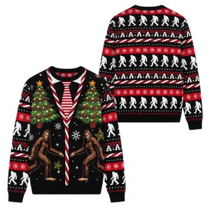 May include: A black long-sleeve jumper featuring a festive holiday pattern with two Bigfoot figures, decorated Christmas trees, and a central red and white striped necktie design. The back displays a repeating pattern of white Bigfoot silhouettes.
