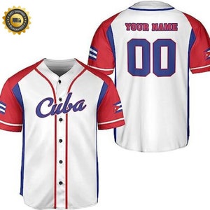 以下が含まれることがあります： 赤と青のトリムが付いた白い野球のユニフォーム。ユニフォームの前には青い筆記体で「キューバ」と書かれており、袖には赤と青のキューバの国旗が描かれています。ユニフォームの後ろには「YOUR NAME」と青い数字「00」が書かれています。