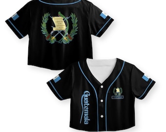 May include: Black baseball jersey with blue trim and the word "Guatemala" in script. The jersey features the Guatemalan coat of arms and flag on the sleeves. The back of the jersey has the coat of arms.