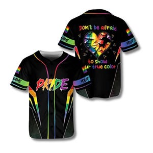 May include: Black baseball jersey with rainbow accents and the word "PRIDE" across the chest. The back of the jersey features a heart design with the text "Don't be afraid to show ur true color". The sleeves have rainbow flag details.