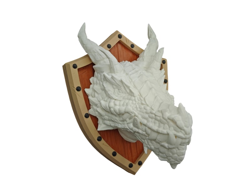 Puede incluir: Escultura de cabeza de drag&oacute;n blanca montada en un escudo de madera con detalles met&aacute;licos. El escudo es marr&oacute;n con un centro rojo.
