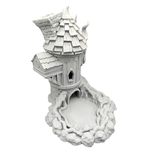 Op de afbeelding: Witte 3D-geprinte toren met een rieten dak en een kleine opening aan de basis. De toren is omringd door een ring van rotsen en wijnstokken.