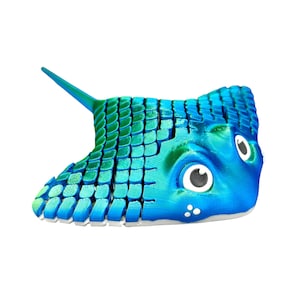 Op de afbeelding: Een blauw en groen rog speelgoed met grote ogen en een textuur. Het speelgoed is gemaakt van plastic en is ontworpen om eruit te zien als een echte rog.