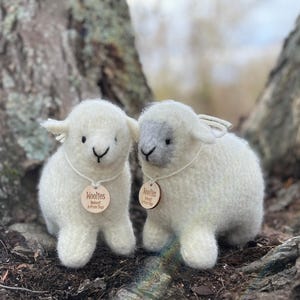 May include: Two white felted sheep toys with wooden tags that say "Woollies" and "Woollies - Handfelted - Artisan Toys".