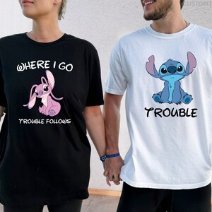 May include: A couple wearing matching t-shirts with a blue and pink Stitch character. The woman's shirt says "Where I go Trouble Follows" and the man's shirt says "Trouble".