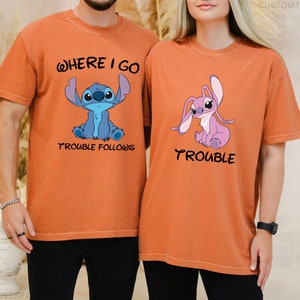 May include: Two orange t-shirts with a blue and a pink Stitch character from the Disney movie Lilo & Stitch. The blue Stitch t-shirt says "Where I go trouble follows" and the pink Stitch t-shirt says "Trouble".