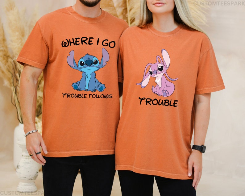 May include: Two orange t-shirts with a blue and a pink Stitch character from the Disney movie Lilo & Stitch. The blue Stitch t-shirt says "Where I go trouble follows" and the pink Stitch t-shirt says "Trouble".