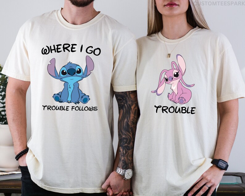 May include: Two white t-shirts with a blue and pink Stitch character from the Disney movie Lilo & Stitch. The blue shirt says "Where I Go Trouble Follows" and the pink shirt says "Trouble".