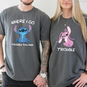 May include: Two gray t-shirts with a cartoon Stitch character. The first shirt says "Where I Go Trouble Follows" and features a blue Stitch. The second shirt says "Trouble" and features a pink Stitch.