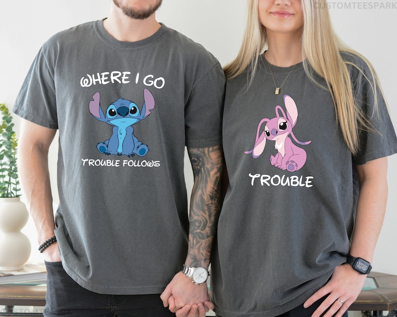 May include: Two gray t-shirts with a cartoon Stitch character. The first shirt says "Where I Go Trouble Follows" and features a blue Stitch. The second shirt says "Trouble" and features a pink Stitch.