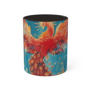 May include: A black and white coffee mug with a colorful image of a phoenix with red, orange, yellow, and blue feathers against a blue background.