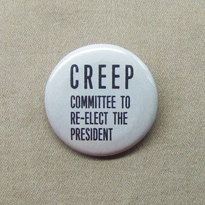 May include: White button with black text that reads "CREEP COMMITTEE TO RE-ELECT THE PRESIDENT".