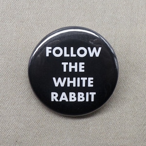 May include: A black button with white text that reads "FOLLOW THE WHITE RABBIT".