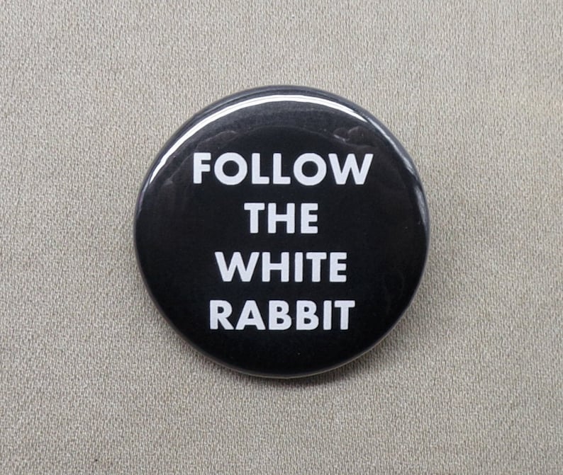 May include: A black button with white text that reads "FOLLOW THE WHITE RABBIT".