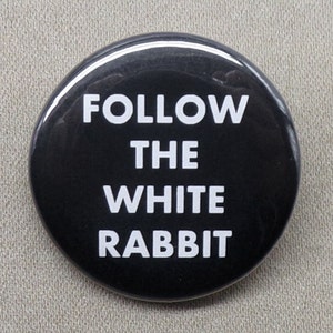 May include: A black button with white text that reads "FOLLOW THE WHITE RABBIT".