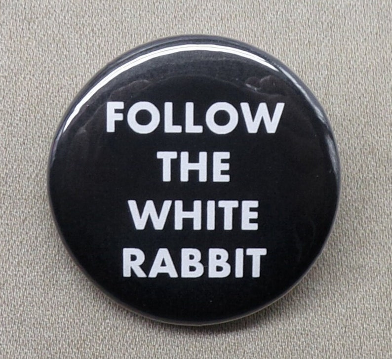 May include: A black button with white text that reads "FOLLOW THE WHITE RABBIT".