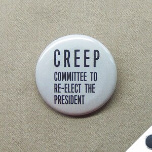 May include: A white button with black text that reads "CREEP COMMITTEE TO RE-ELECT THE PRESIDENT".