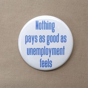 May include: White button with blue text that reads "Nothing pays as good as unemployment feels."