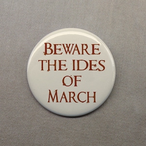 May include: White button with brown text that reads "Beware the Ides of March."