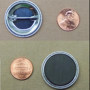 May include: A silver-coloured button with a pin back and a black magnet button. Two pennies are next to the buttons for size comparison. The button is round.