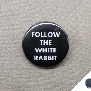 May include: A black button with white text that reads "FOLLOW THE WHITE RABBIT".