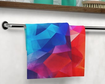 May include: A colorful hand towel with a geometric pattern in shades of blue, red, and purple. The towel is hanging on a silver towel rack.