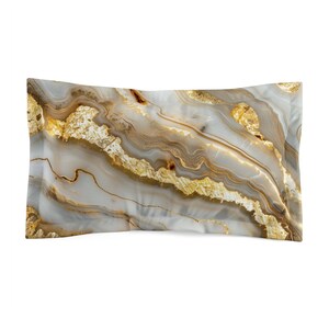 May include: A rectangular pillowcase with a marbled design. The pillowcase features a blend of white, gray, and brown tones, with gold accents. The design resembles natural stone, creating a luxurious aesthetic.