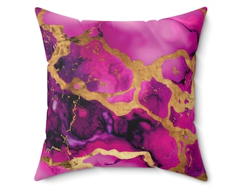 May include: Square throw pillow with a vibrant abstract design. The pillow features a blend of pink, magenta, and purple hues, accented with gold-colored, vein-like patterns. The pillow has a soft, textured appearance and is likely made of a comfortable fabric.