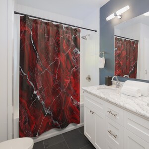 May include: A red and black marble-patterned shower curtain hangs in a bathroom. White veins run through the red and black design. The bathroom has white cabinets, a marble countertop, and a silver faucet.