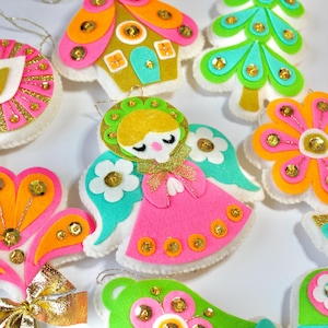 Könnte beinhalten: Ein Set mit 10 Vintage-Weihnachtsbaumschmuck aus Filz mit einem Retro-Design aus den 1960er Jahren. Der Schmuck zeigt eine Vielzahl von Formen, darunter einen Baum, ein Haus, eine Blume, einen Engel und einen Stiefel. Der Schmuck ist mit Pailletten und Glitzer in den Farben Pink, Grün, Orange und Gelb verziert.
