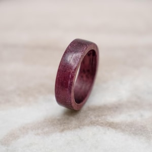 May include: A dark purple wooden ring with a smooth, polished finish.